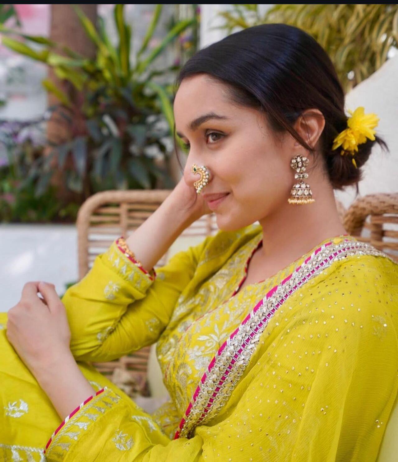 Shraddha Kapoor looks as bright as ever in a yellow kurta set with silver details and contrasting borders. She accessorises her look with kundan jhumkas and tops it off with a crescent-shaped nath, giving an entirely different flavour to her outfit. 